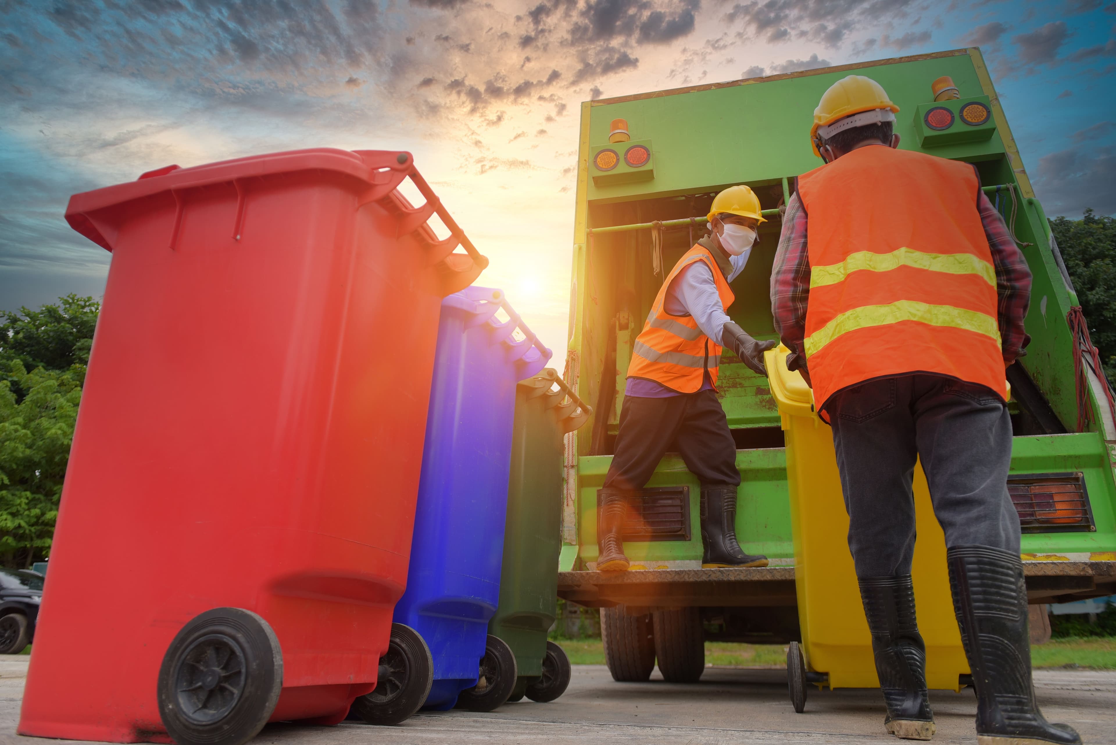 Two refuse collectors empty a recycling bin into a truck